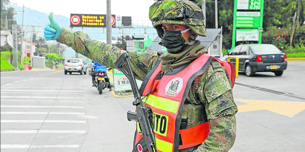 Un soldado del Ejército saludaba ayer en un puesto de control en la carretera que une a Bogotá y La Calera, mientras usa mascarilla y guantes para prevenir la propagación del virus Covid-19.