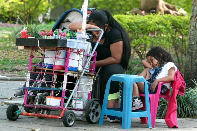 Una madre y su pequeña venden en el parque Bolívar, vencidas por el sueño.