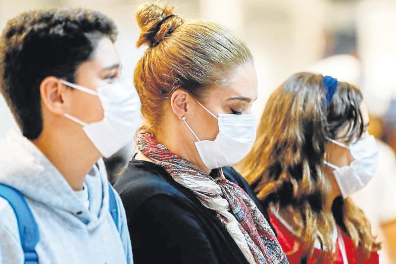 Pasajeros usan máscaras como precaución contra la propagación del nuevo coronavirus Covid-19 durante su llegada, ayer, al Aeropuerto Internacional de Sao Paulo (Brasil).