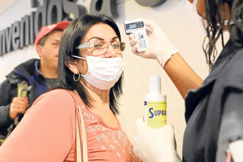 Funcionarios toman la temperatura de los ciudadanos en el aeropuerto internacional El Dorado, como parte de las medidas de prevención para despachar y recibir pasajeros, en Bogotá.