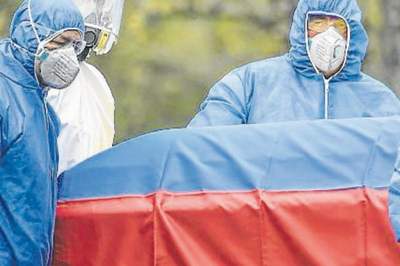 Trabajadores del cementerio usan un traje protector mientras se prepara para llevar el ataúd del médico colombiano William Gutiérrez, quien murió de Covid-19 en Bogotá el 12 de abril de 2020