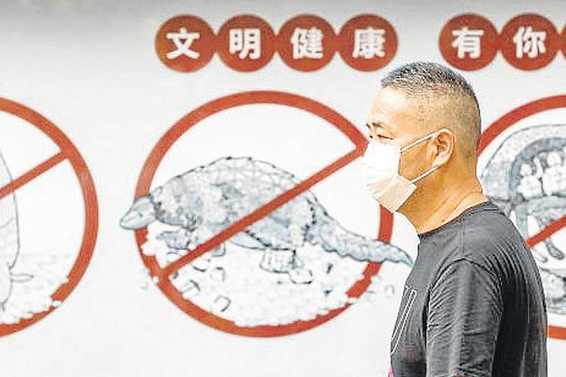 Un hombre camina junto a un cartel que prohibe el consumo de animales silvestres, en Guangzhou, China.