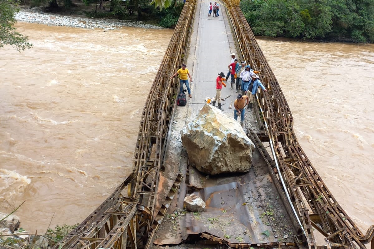 En el puente Las Señoritas, ubicado entre Chaparral y Rioblanco, las personas se arriesgan para cruzar por los lados de la piedra que los tiene pasando penas, la misma está siendo retirada a mano por los lugareños.