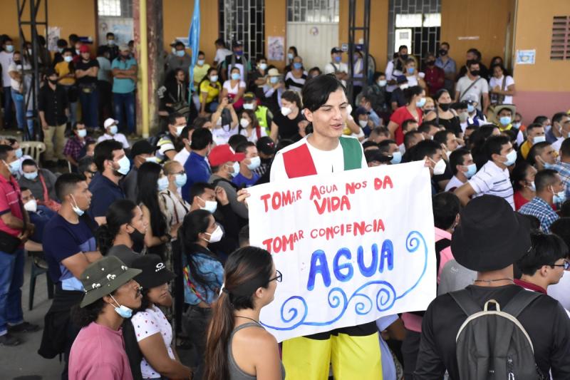 Joven con cartel alusivo a la protección del agua en los territorios 